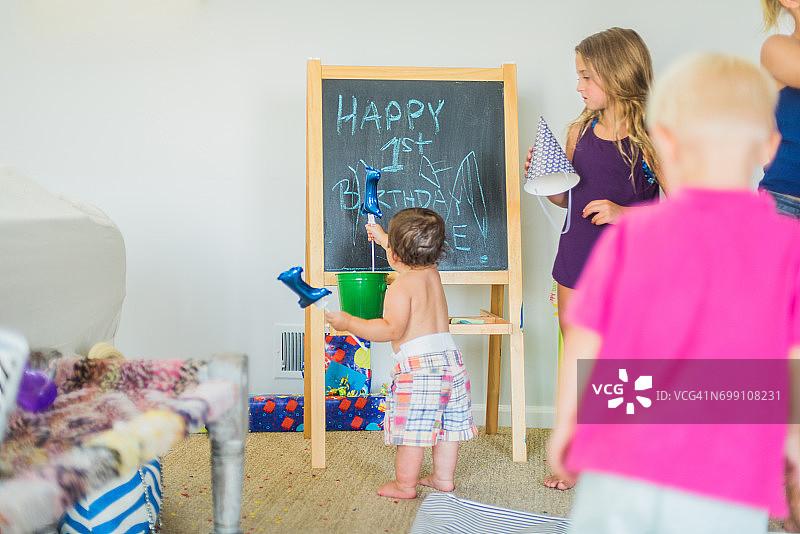 在生日派对上、在黑板旁玩气球的幼童图片素材