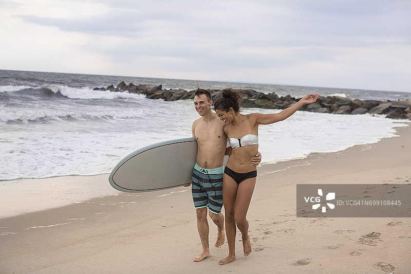 在纽约州罗卡韦海滩漫步的浪漫年轻冲浪情侣图片素材