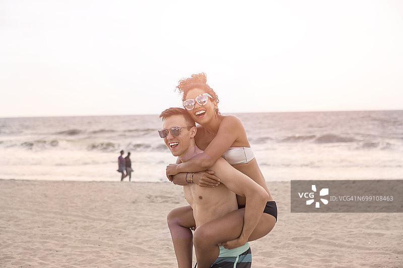 纽约州洛克威海滩上背着女友的年轻男子图片素材