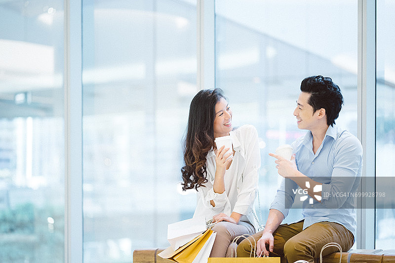 年轻的亚洲情侣在购物中心享受购物图片素材