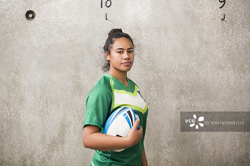 在更衣室里手持橄榄球的女子橄榄球运动员图片素材