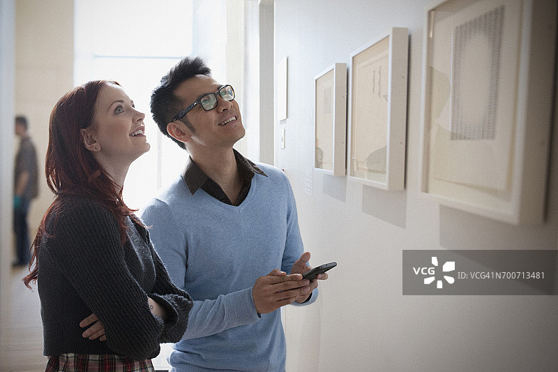 情侣在画廊用手机欣赏艺术品图片素材