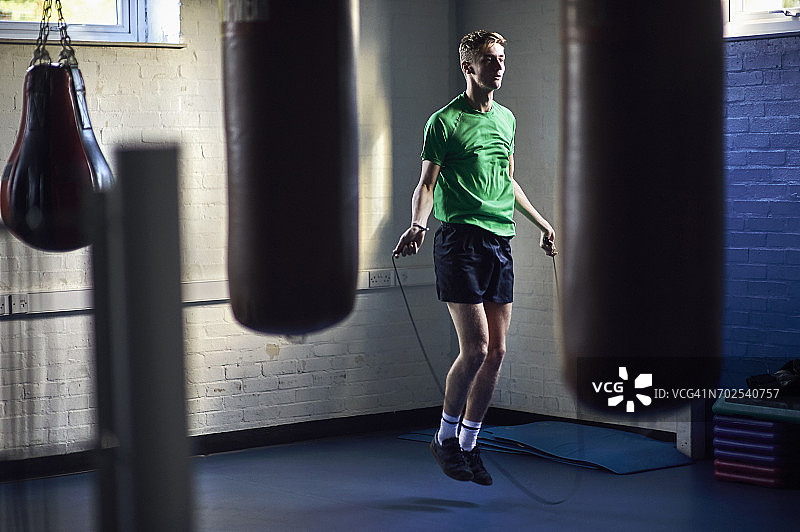 在健身房跳绳的年轻男拳击手图片素材