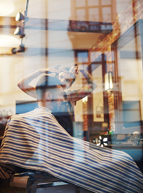透过窗户看理发师为顾客理发图片素材