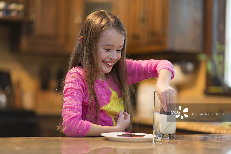 年轻女孩在厨房的桌旁喝牛奶和饼干图片素材
