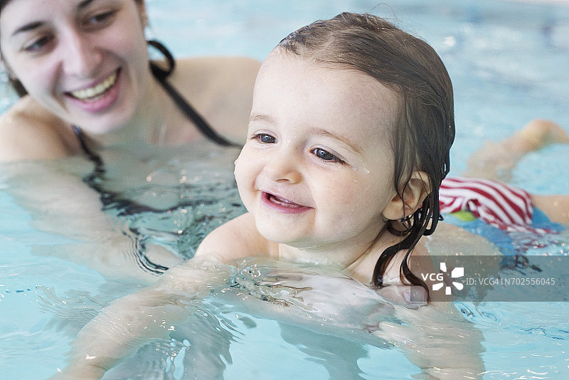 小女孩在父母的帮助下学习游泳图片素材