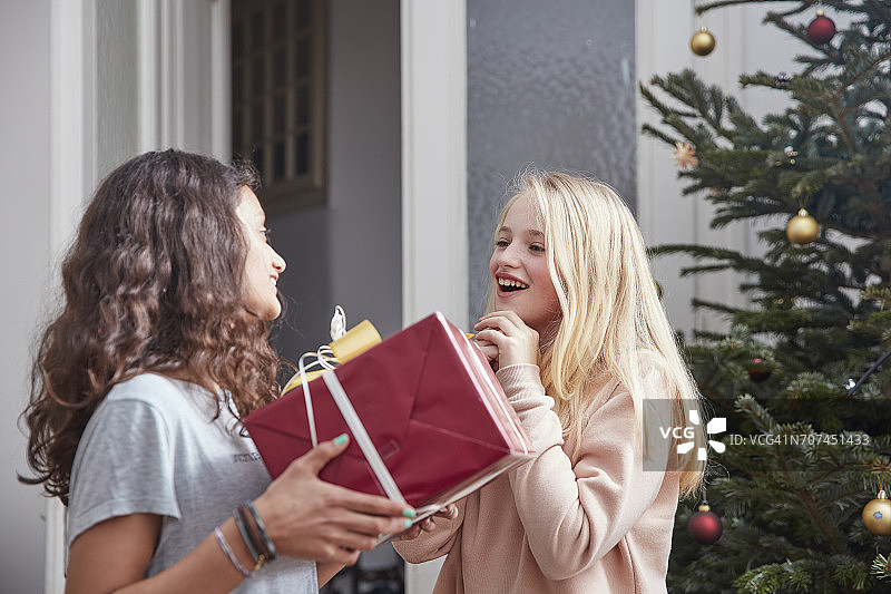 女孩递给朋友圣诞礼物图片素材