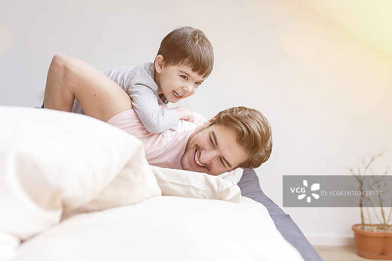 快乐的父子在床上玩耍图片素材