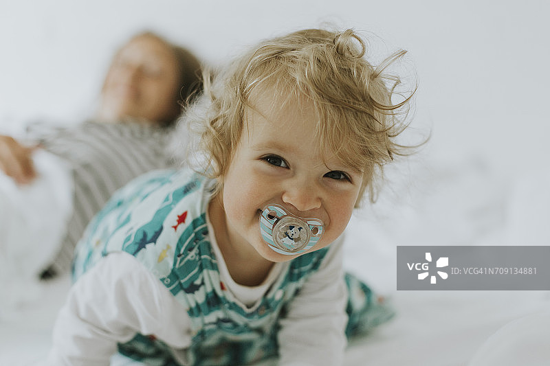 在床上与母亲在一起的快乐小女孩肖像图片素材