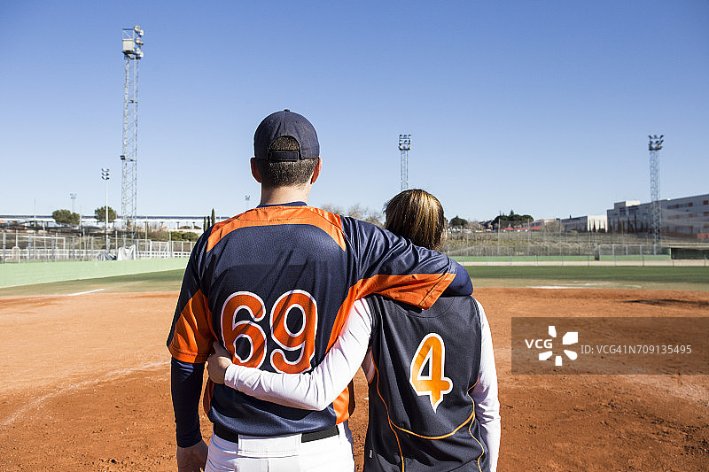 棒球场上拥抱的男女棒球运动员的背影图片素材