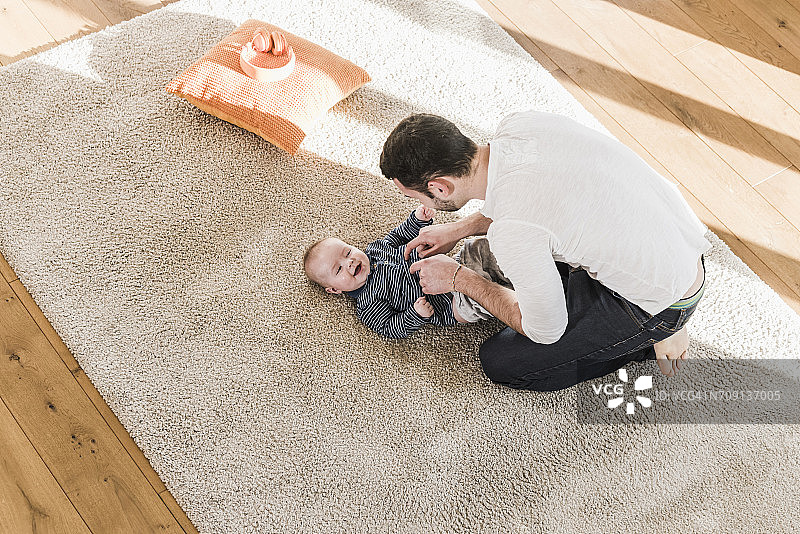 父亲给儿子换尿布并和他玩耍图片素材