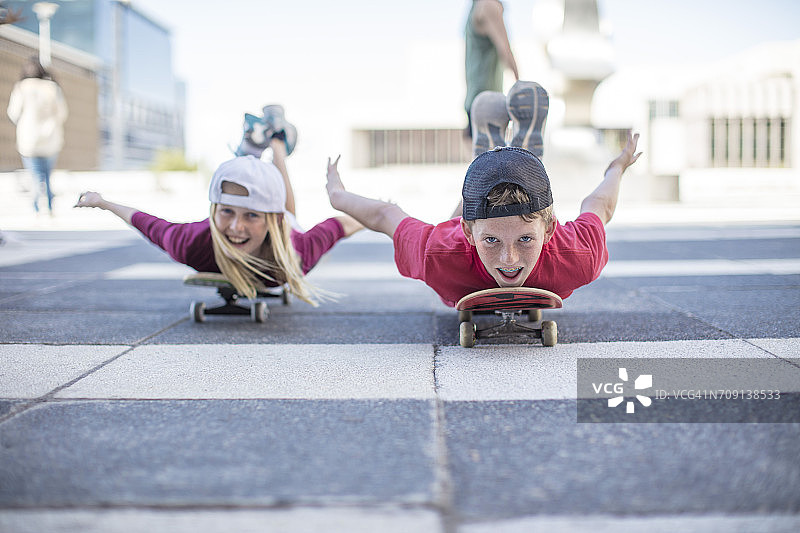 孩子们在街上玩滑板，趴在地上图片素材