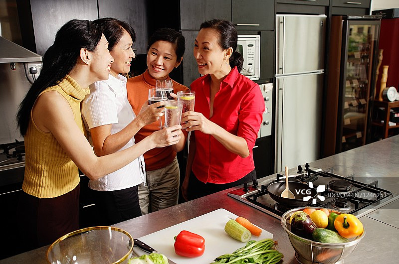 在厨房里拿着酒杯敬酒的女人图片素材