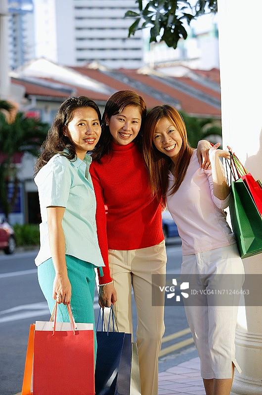 三名女子站立，携带购物袋，对着镜头微笑图片素材