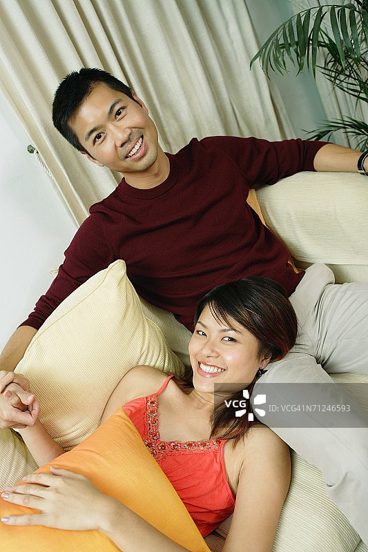 情侣在客厅里，女人躺在男人腿上对着相机微笑图片素材