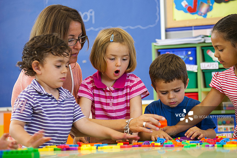 女老师在教室里教学龄前儿童学习字母图片素材
