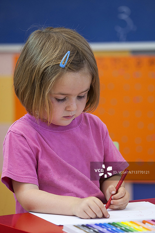 学龄前女孩在教室里用彩色笔图片素材