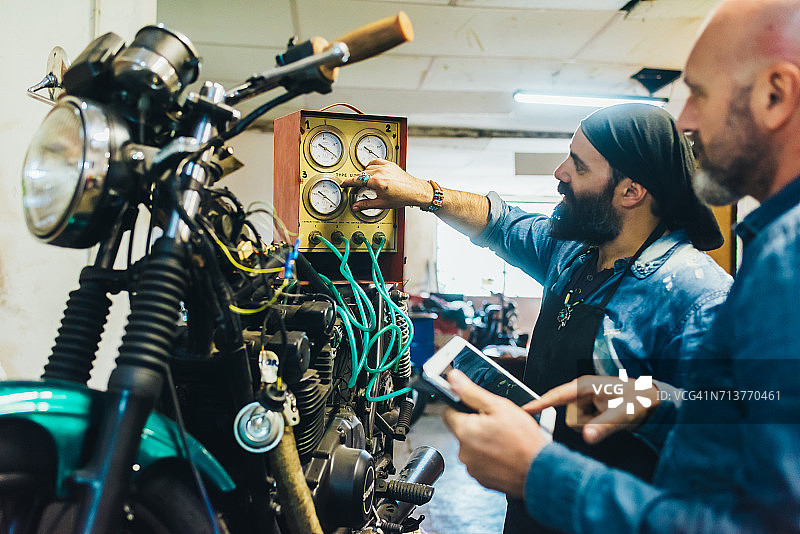 两位中年男人在车库修理摩托车图片素材