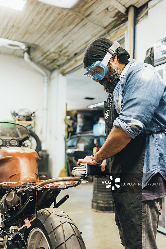 在车库修理摩托车的年长男人图片素材