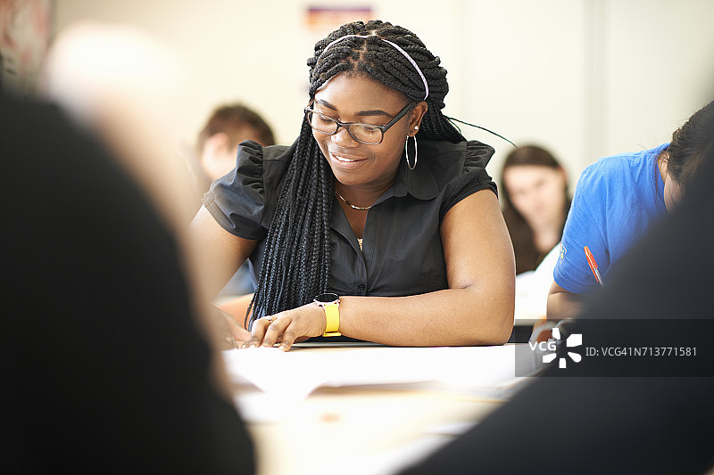 青少年女学生在大学教室的桌子上写作图片素材