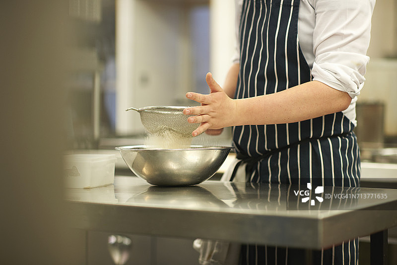 餐饮专业的男学生在学院里将面粉筛入碗中（中段）图片素材