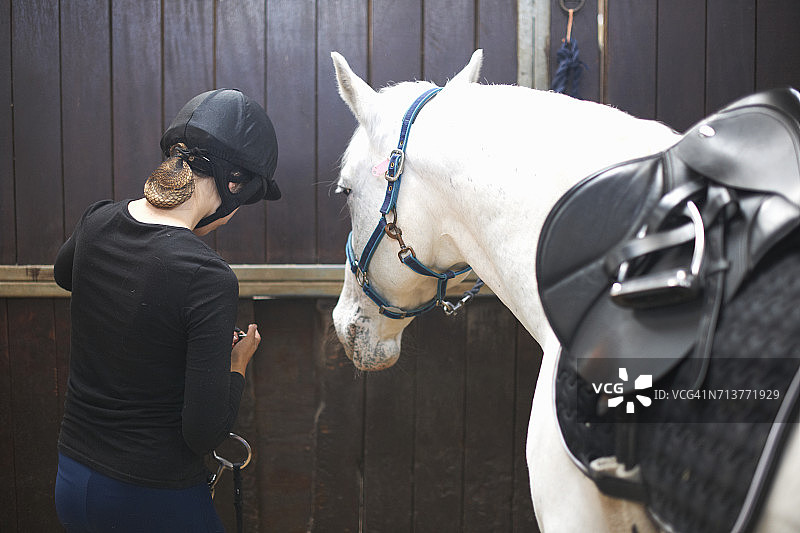 站在马厩里，背对着镜头的年轻女子图片素材