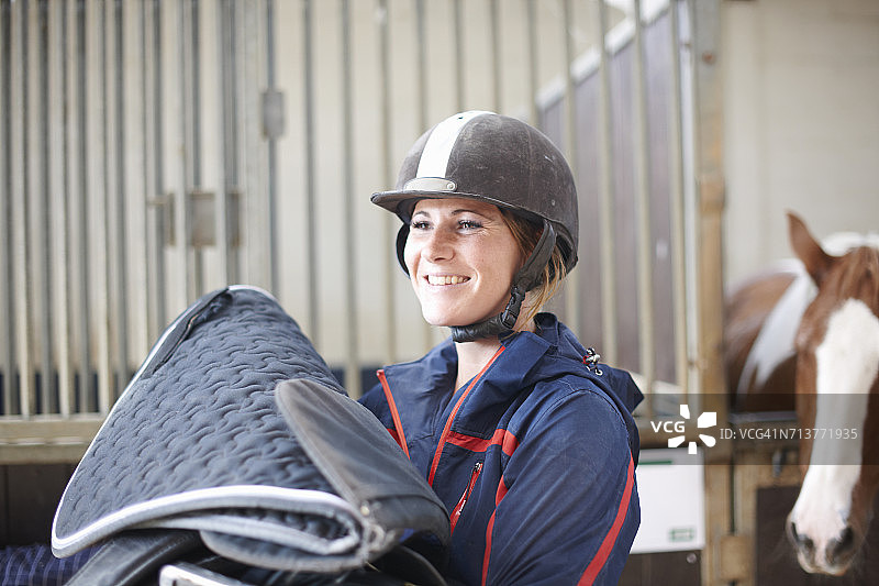 年轻女人拿着马毯和马鞍图片素材