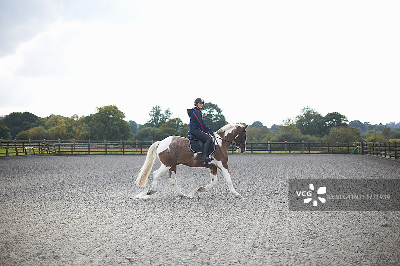 在围场周围骑马的年轻女子图片素材