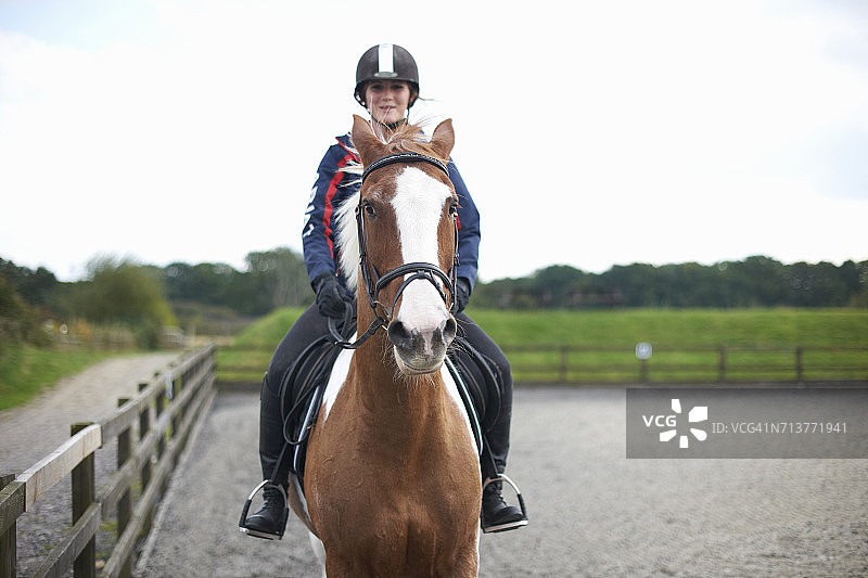 在围场周围骑马的年轻女子图片素材