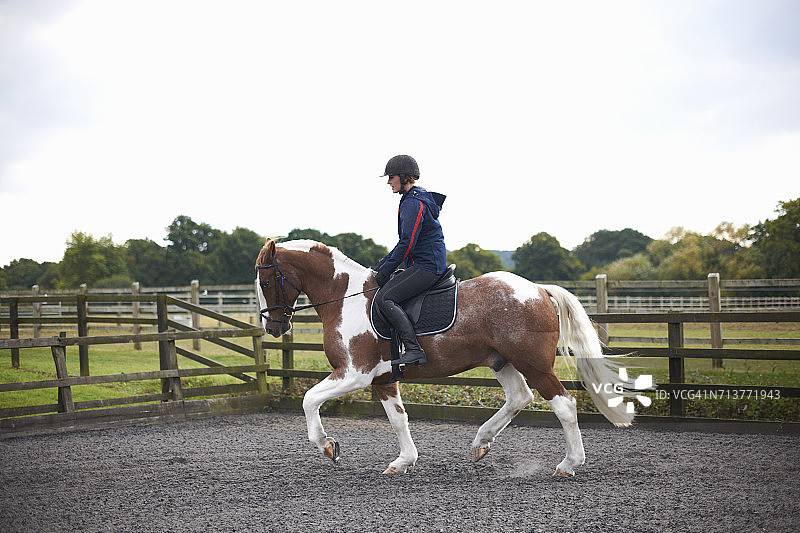 在围场周围骑马的年轻女子图片素材