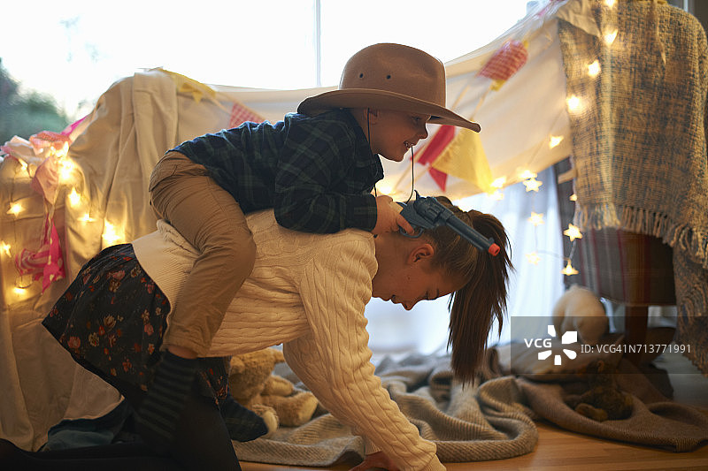 戴着牛仔帽的男孩骑在姐姐的背上图片素材