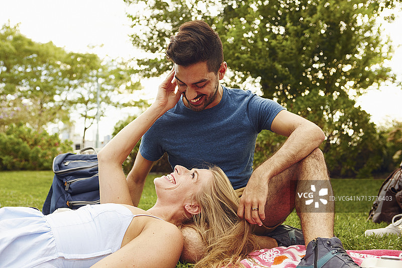 年轻女人在公园里把头放在朋友的腿上放松图片素材