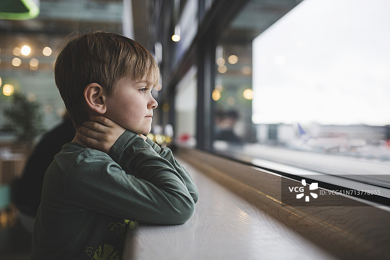 倚靠餐厅窗边桌子的沉思男孩图片素材