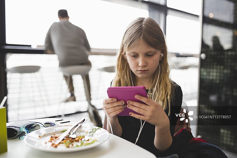 在餐厅的桌旁使用平板电脑的女孩图片素材