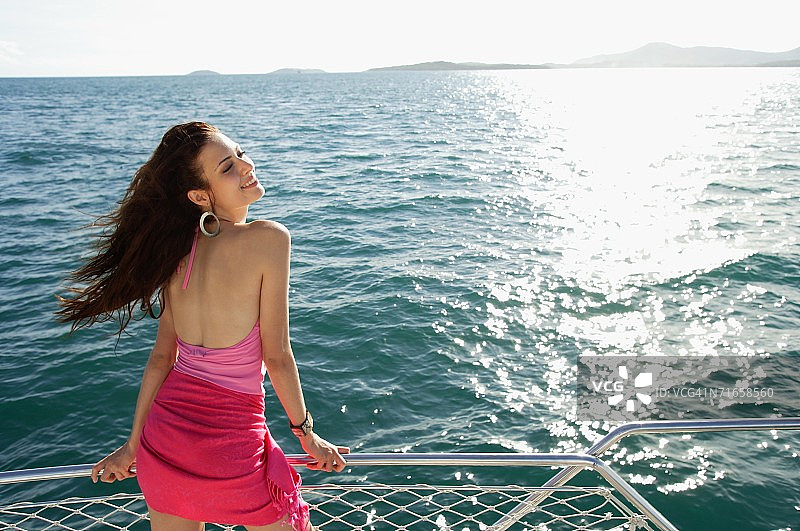 在船上站在栏杆旁享受微风的女人图片素材