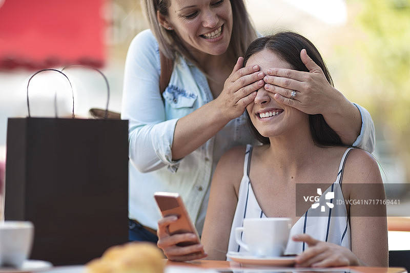 女人在户外咖啡馆捂住朋友的眼睛图片素材