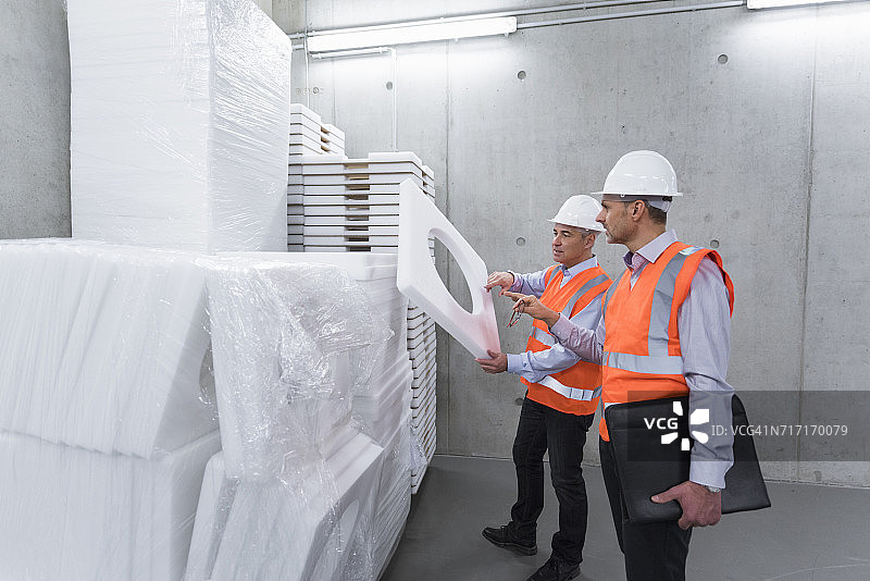 两位同事戴着安全背心和安全帽检查聚苯乙烯图片素材
