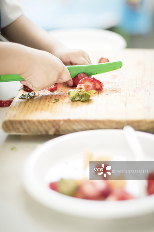 西班牙裔男孩用塑料刀切草莓图片素材