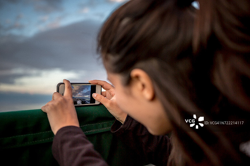 年轻女人在美国缅因州海岸的船上拍摄日落图片素材