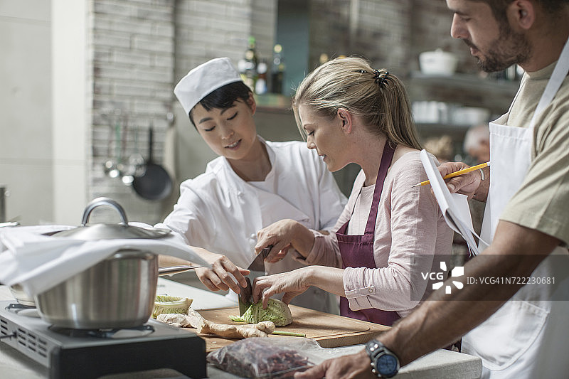 烹饪课上，参与者和女厨师在切卷心菜图片素材