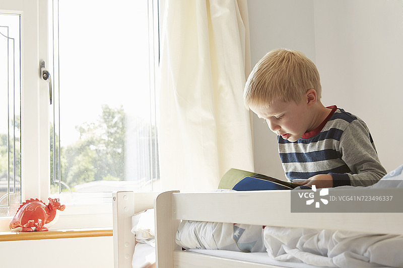 坐在床上看书的男孩图片素材