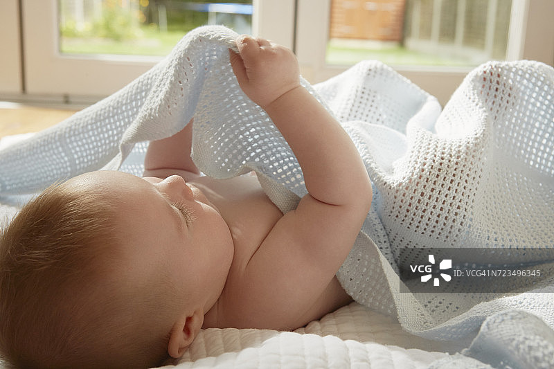 躺在毯子上玩耍的男婴图片素材