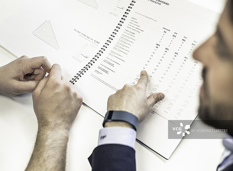 两位商人在办公桌前指着文件图片素材