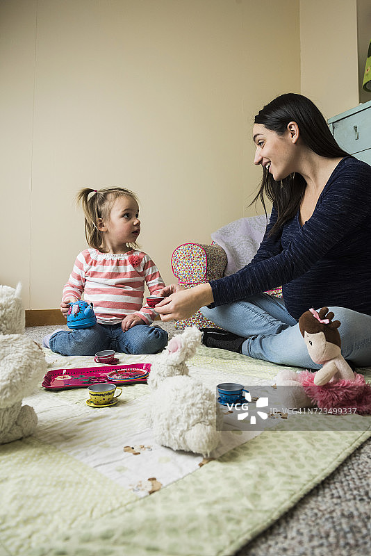 女童坐在地板上与怀孕的母亲玩软玩具野餐图片素材