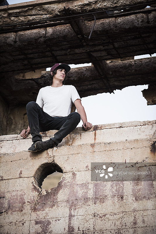 年轻男人坐在废弃矿井的墙上图片素材