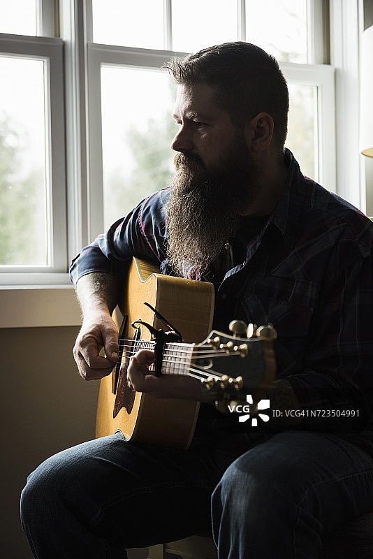 男人在窗边弹吉他图片素材