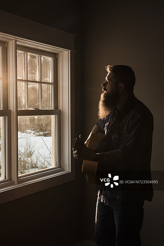 男人在窗边弹吉他图片素材