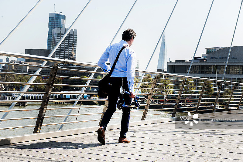 携带滑板车的商人，背景为英国伦敦亨格福德桥图片素材