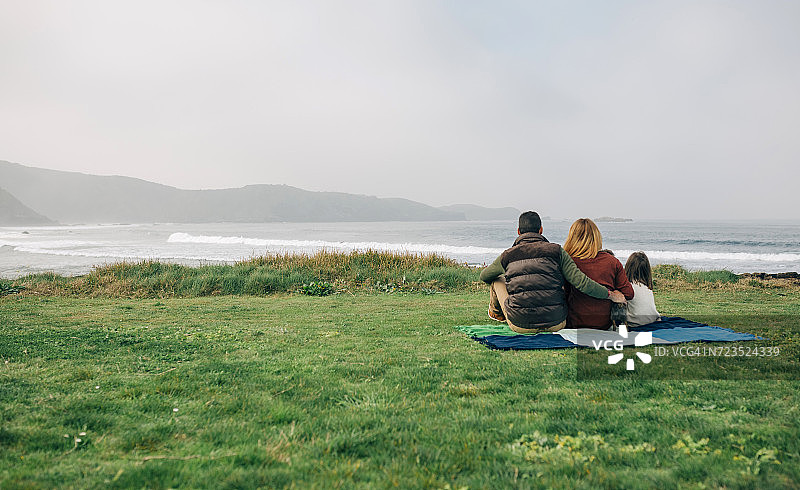 一家人与狗在海边毯上的背影图片素材