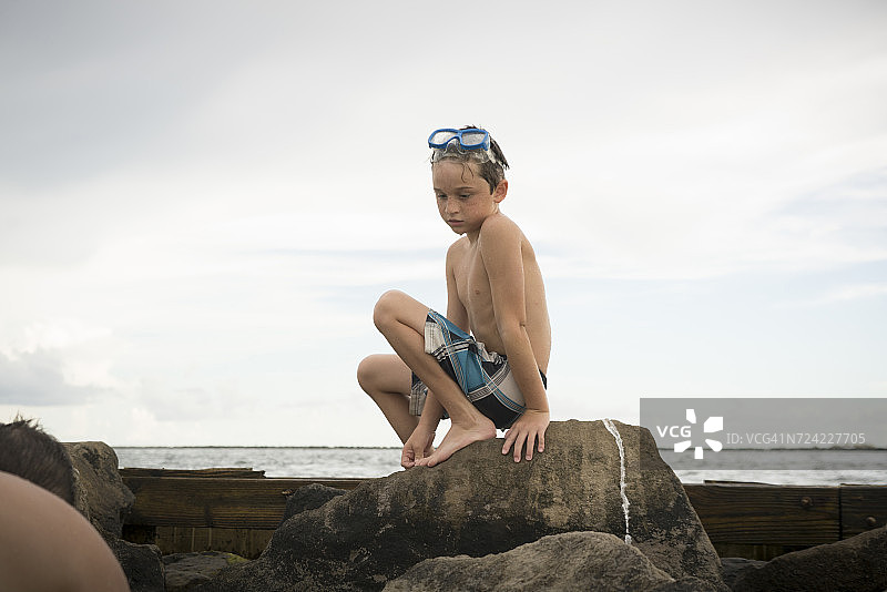 男孩在墨西哥湾翡翠海岸的岩石池中玩耍，美国佛罗里达州图片素材
